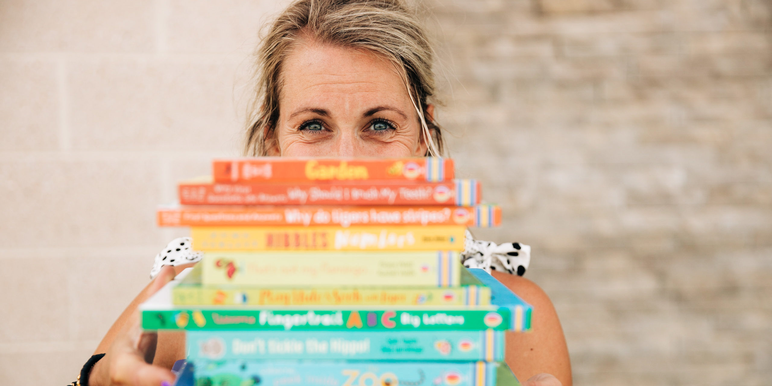 Brand image of woman holding a stack of books.